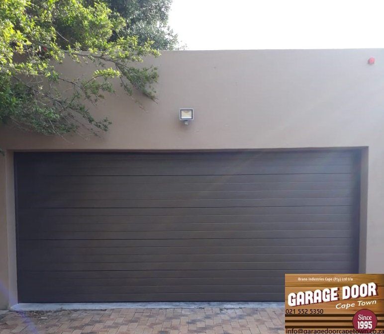Dark brown horizontal panel garage door on a tan wall.