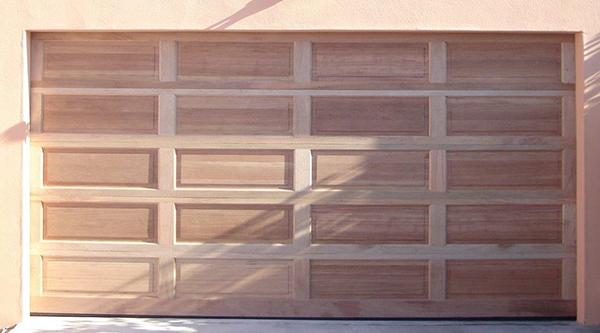 Wooden garage door with a rectangular panel design, in natural wood color.