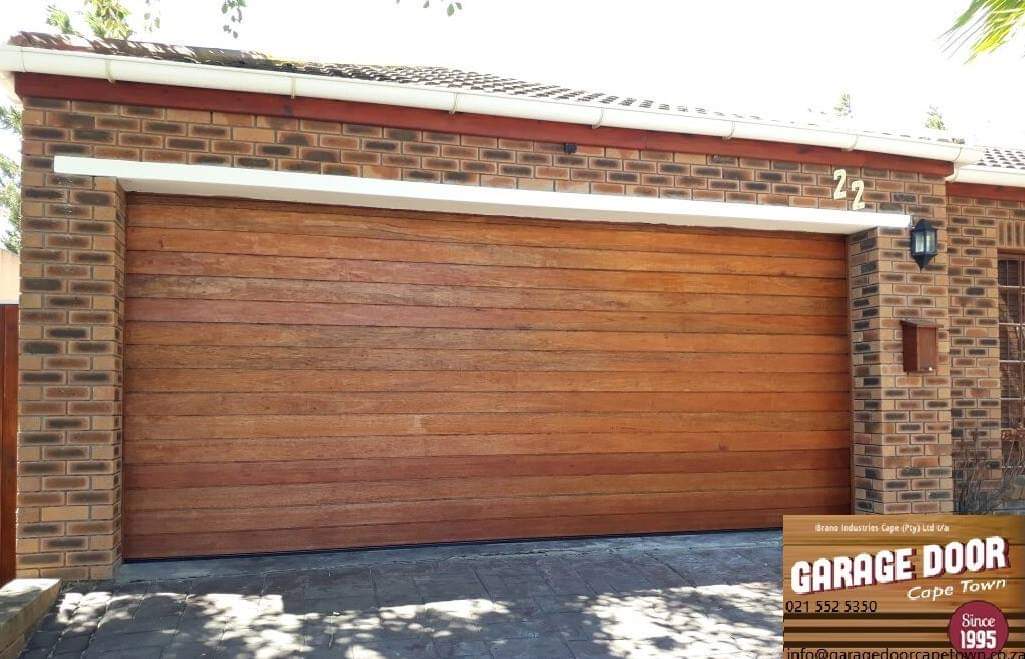Brown wooden garage door with brick facade.