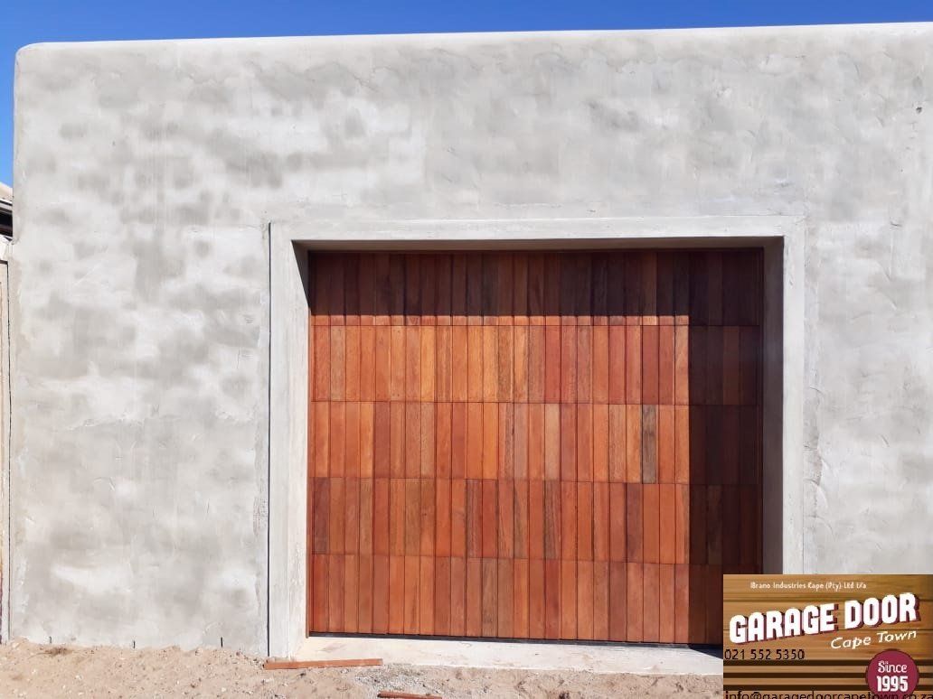 Wooden garage door set in a gray stucco wall.
