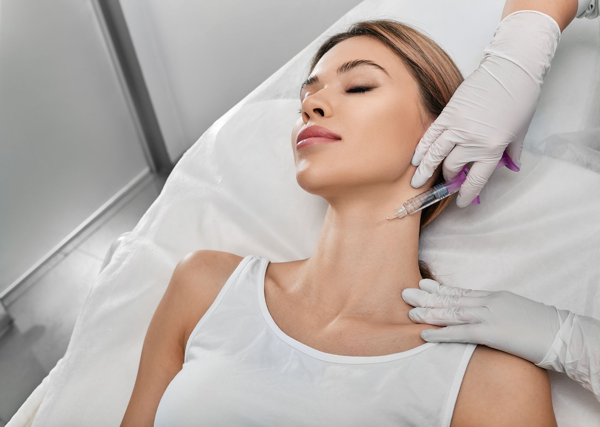 Woman receiving neck injections from gloved hands in a clinical setting.
