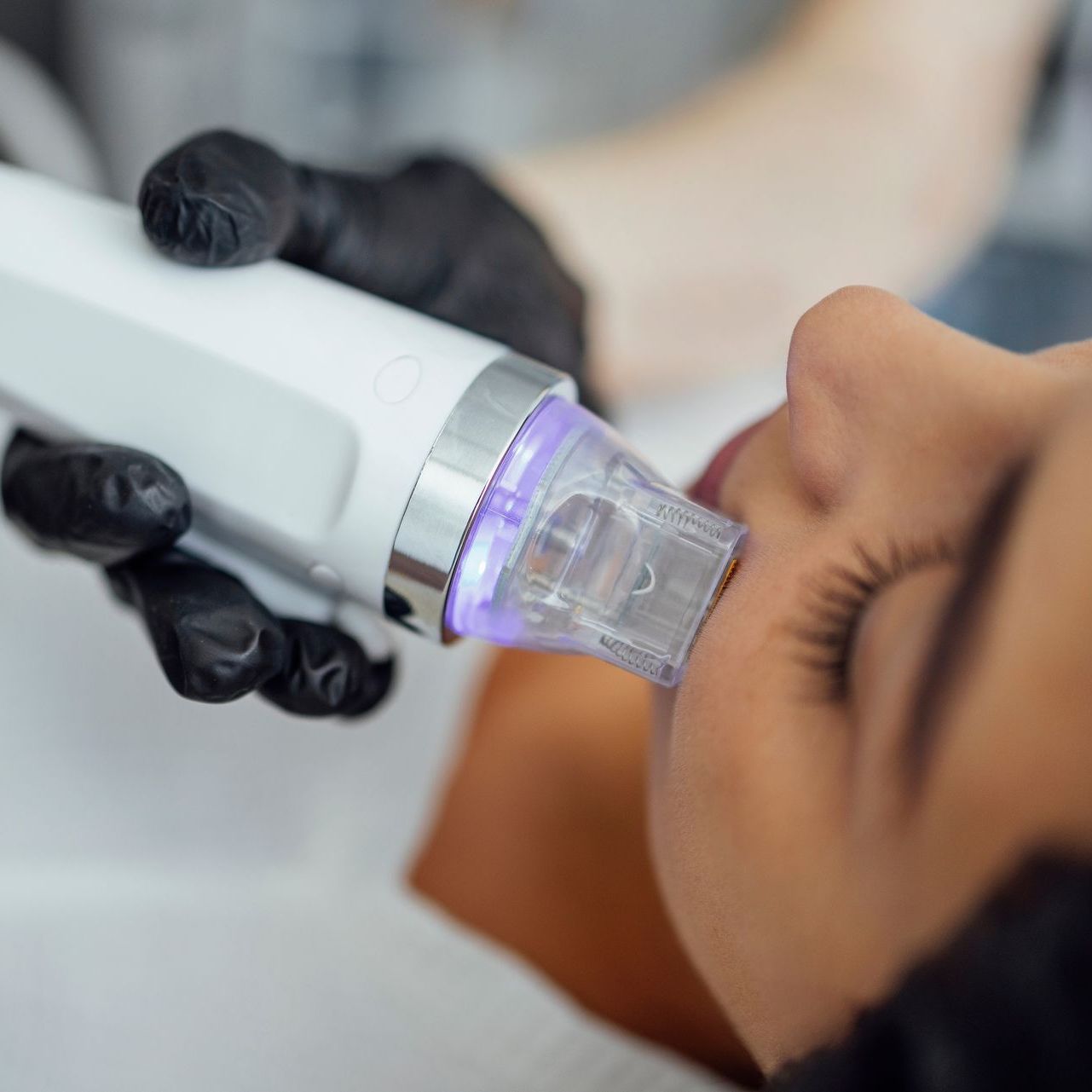 A woman is getting a facial treatment with a machine.