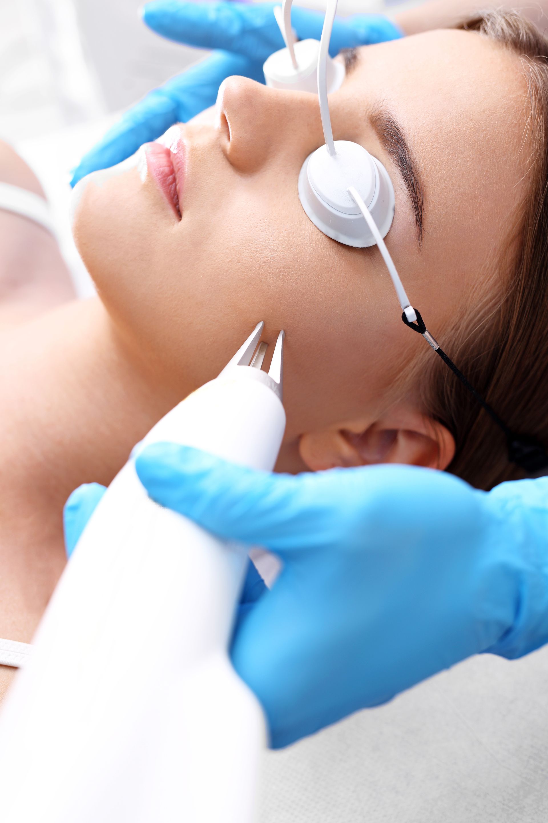 A woman is getting a laser treatment on her face.