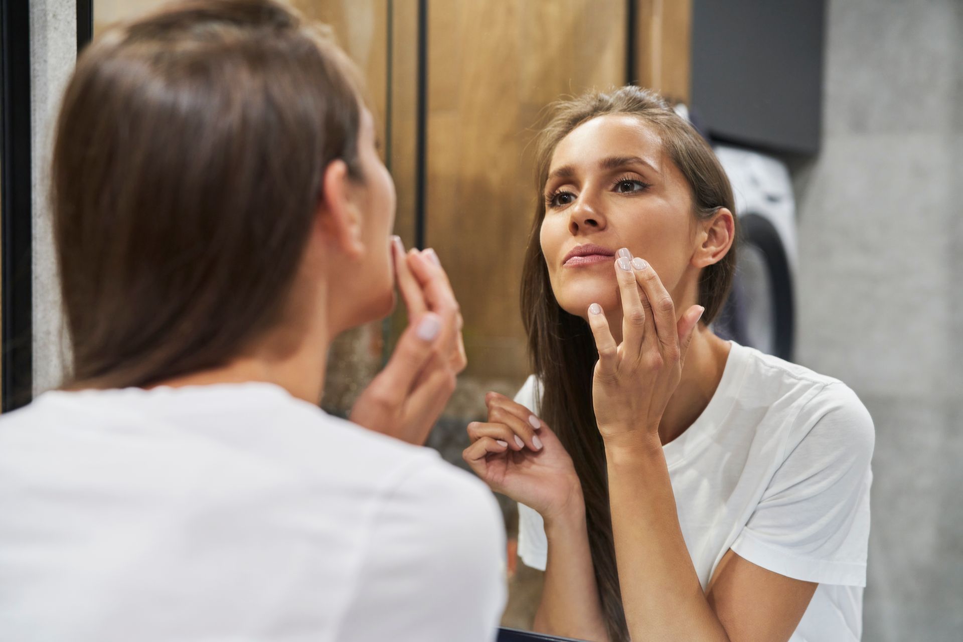 woman looking at face in mirror