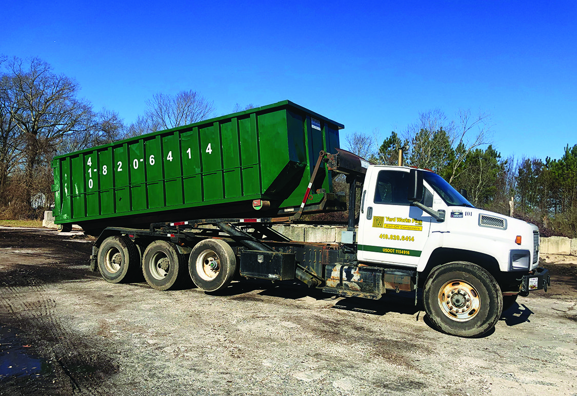 Yard Works Plus 30 yard dumpster on a gravel lot under a blue sky.
