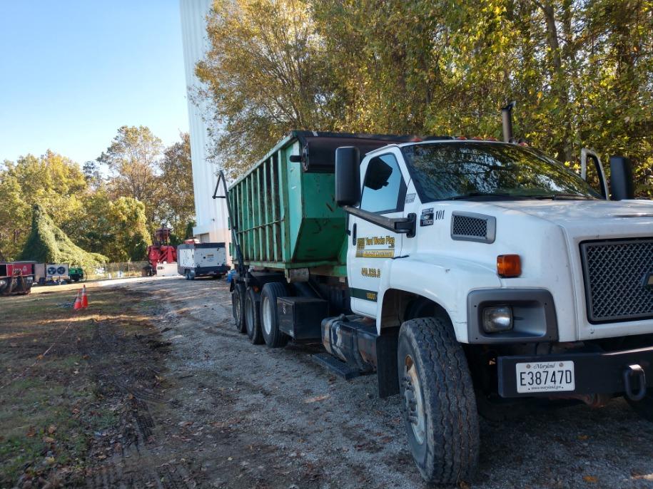 Yard Works Plus dumpster being delivered to an industrial construction jobsite