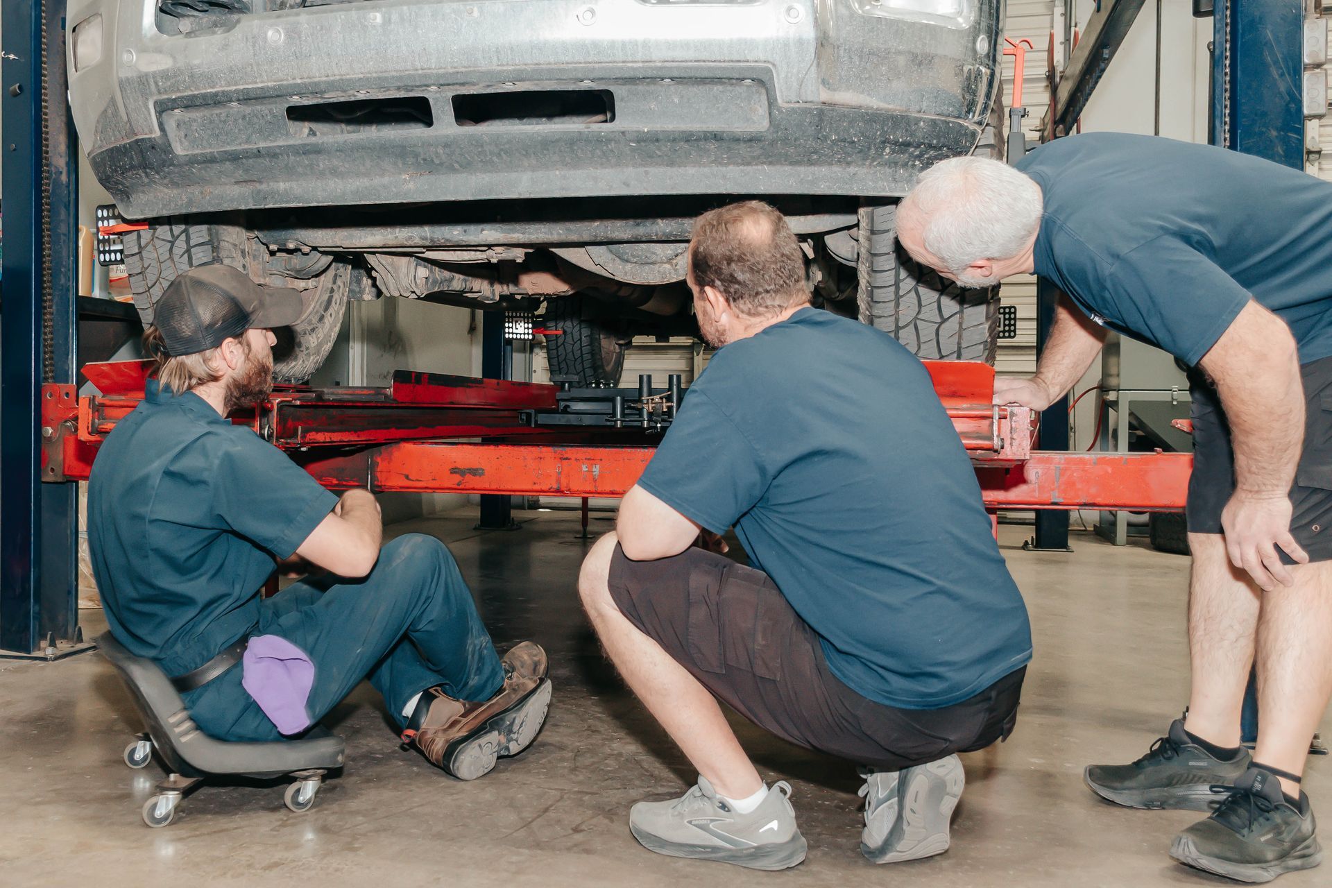 Mechanic inspecting a silver SUV’s front wheel in an auto repair shop