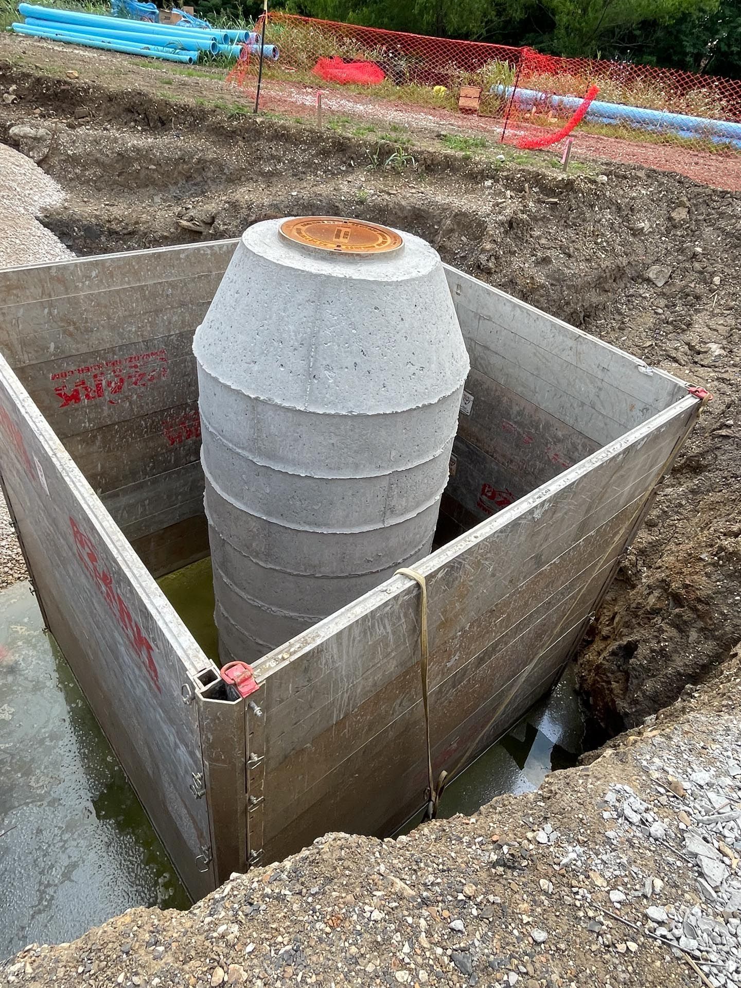 A manhole cover is sitting in the middle of a dirt field.