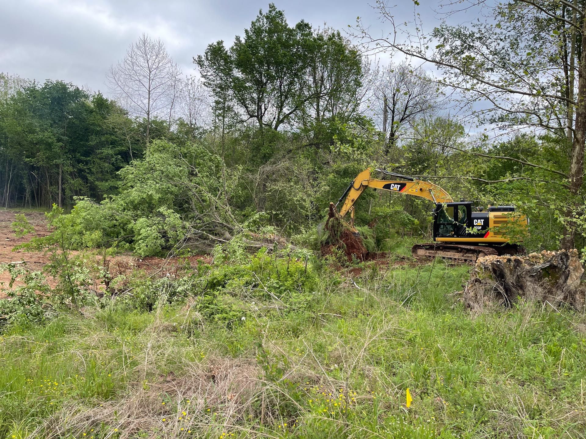 A man is driving a cat excavator in a dirt field