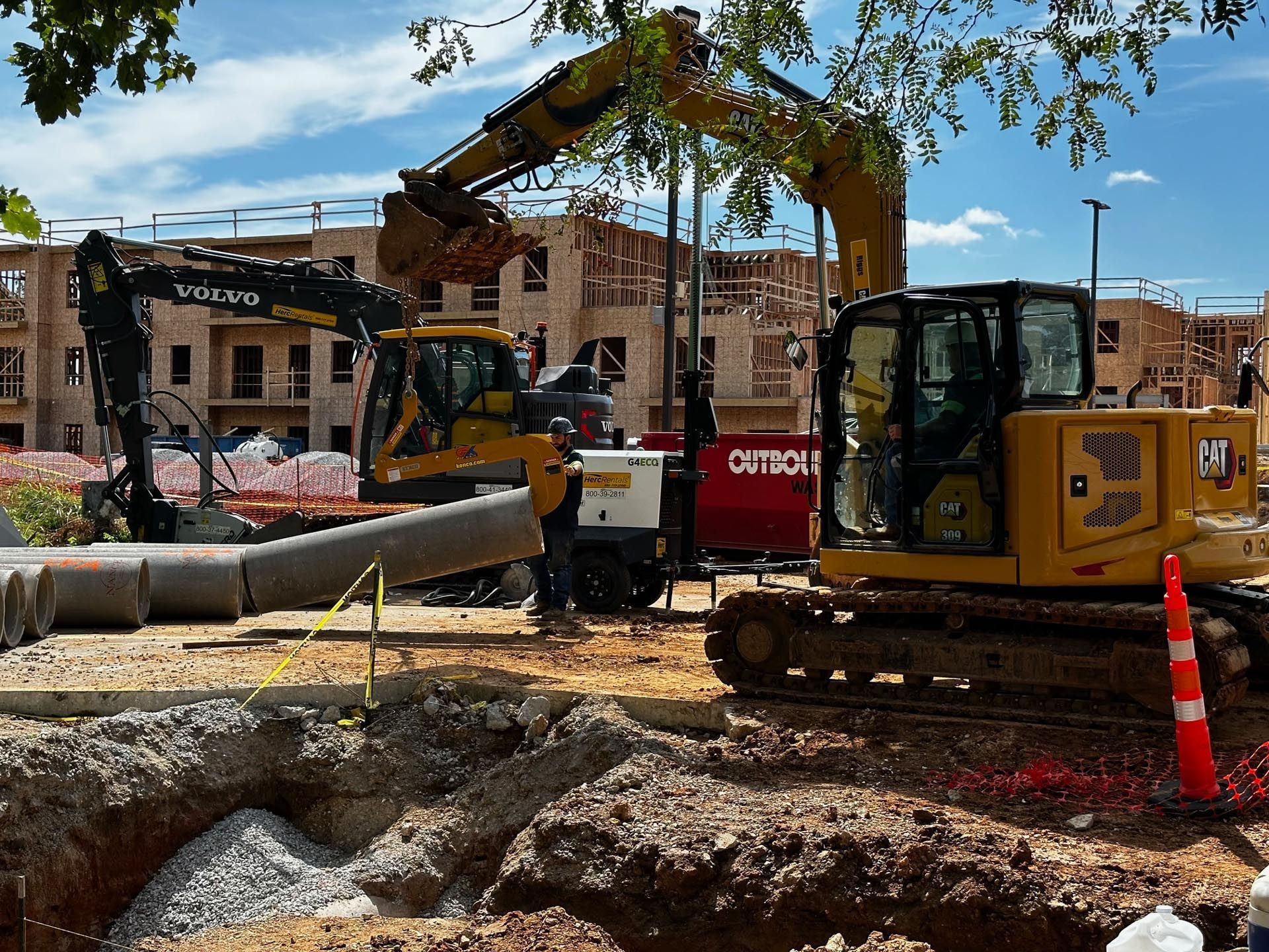 A bulldozer is digging a trench in the dirt next to a car.