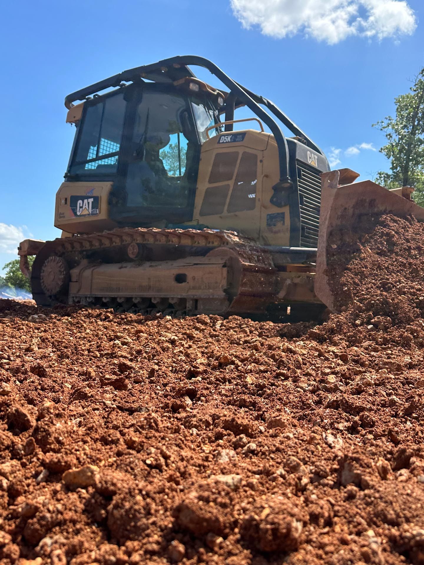 A construction site with a lot of dirt and trees in the background.