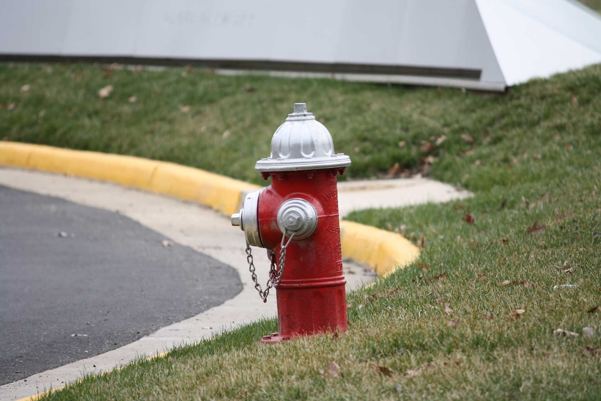 A red fire hydrant is sitting on the side of the road.