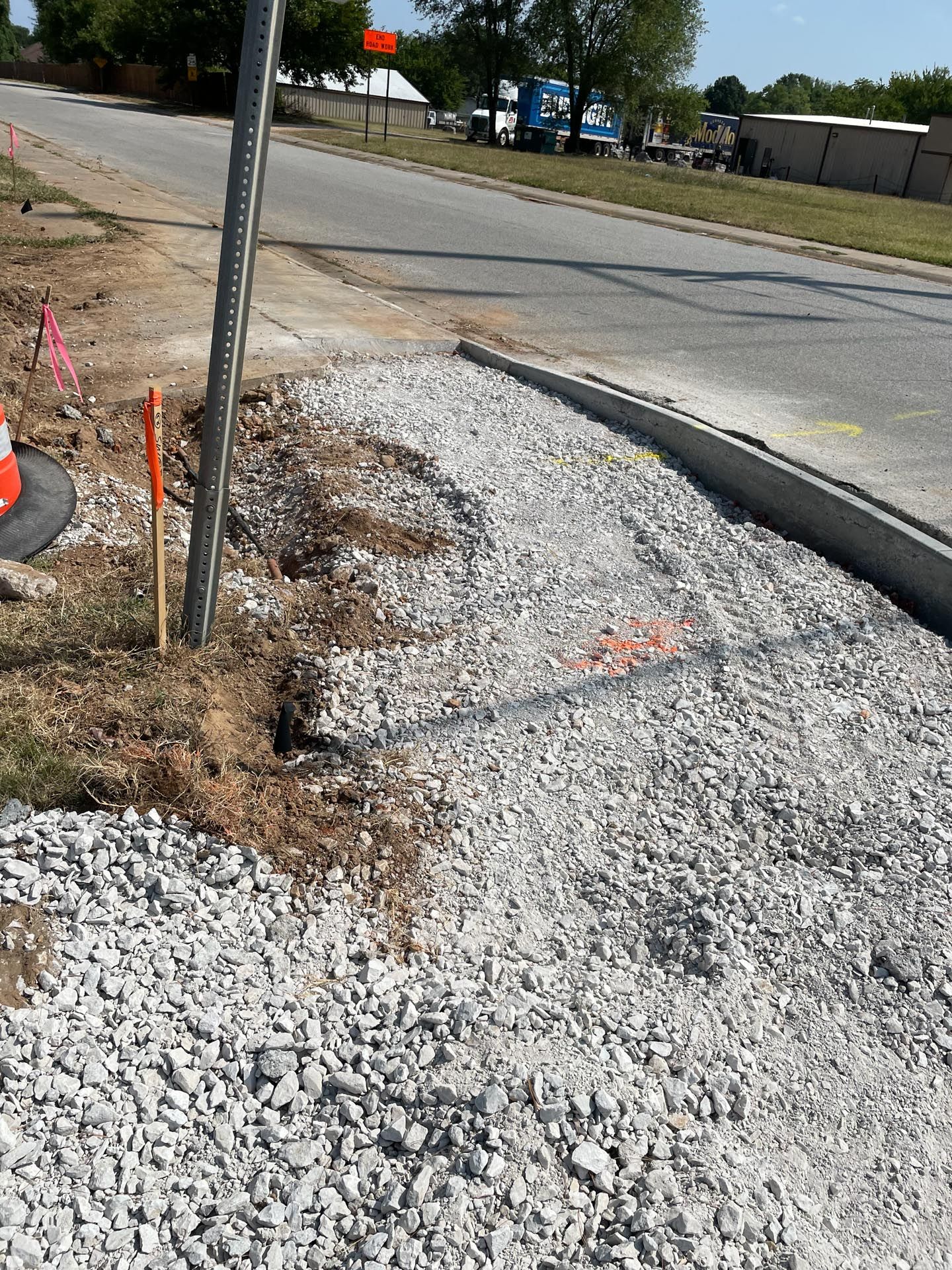 A person is standing on a pile of gravel next to a road.