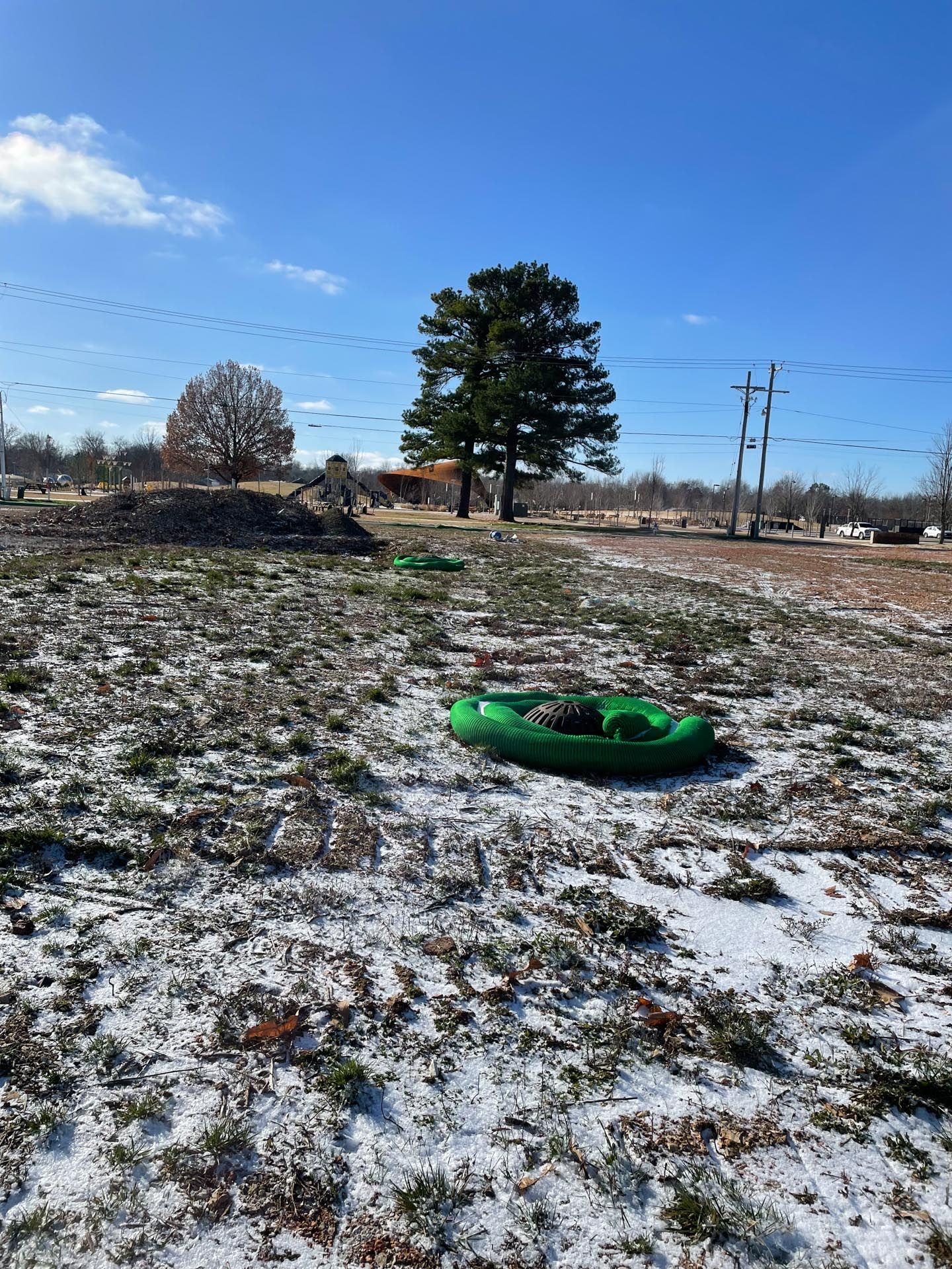 A person is riding a green tube down a snow covered field.