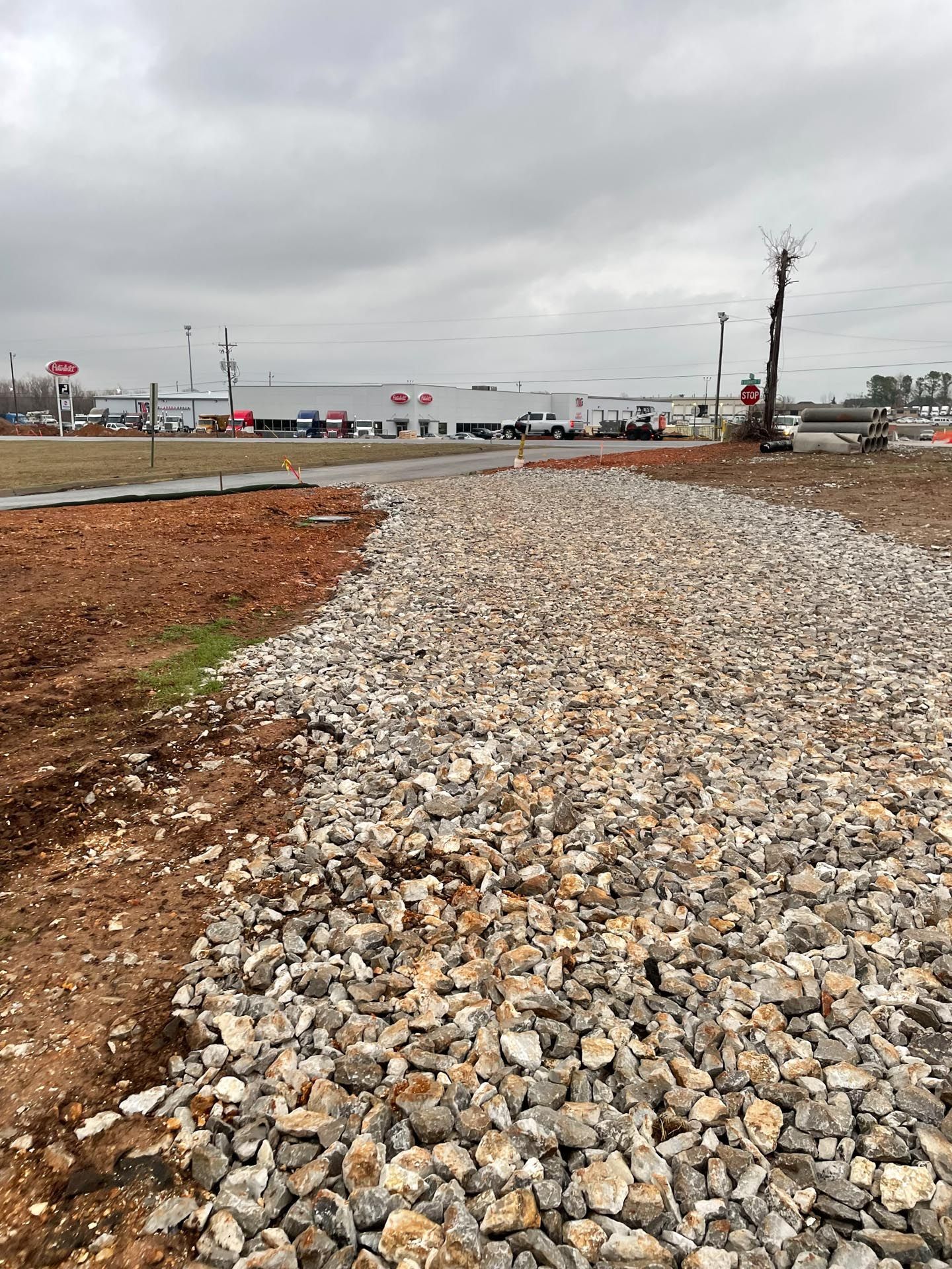 A pile of gravel is sitting in the middle of a dirt field.