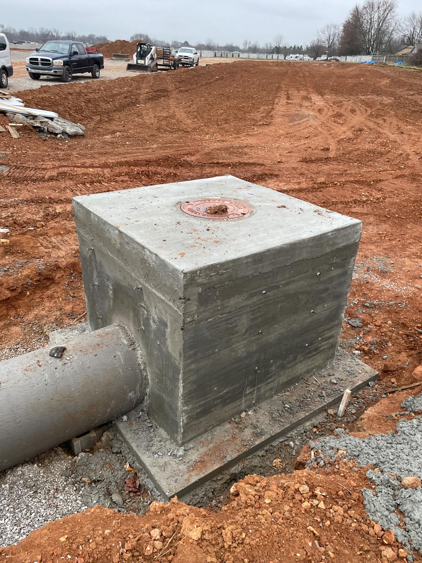 A concrete block is sitting in the middle of a dirt field next to a pipe.