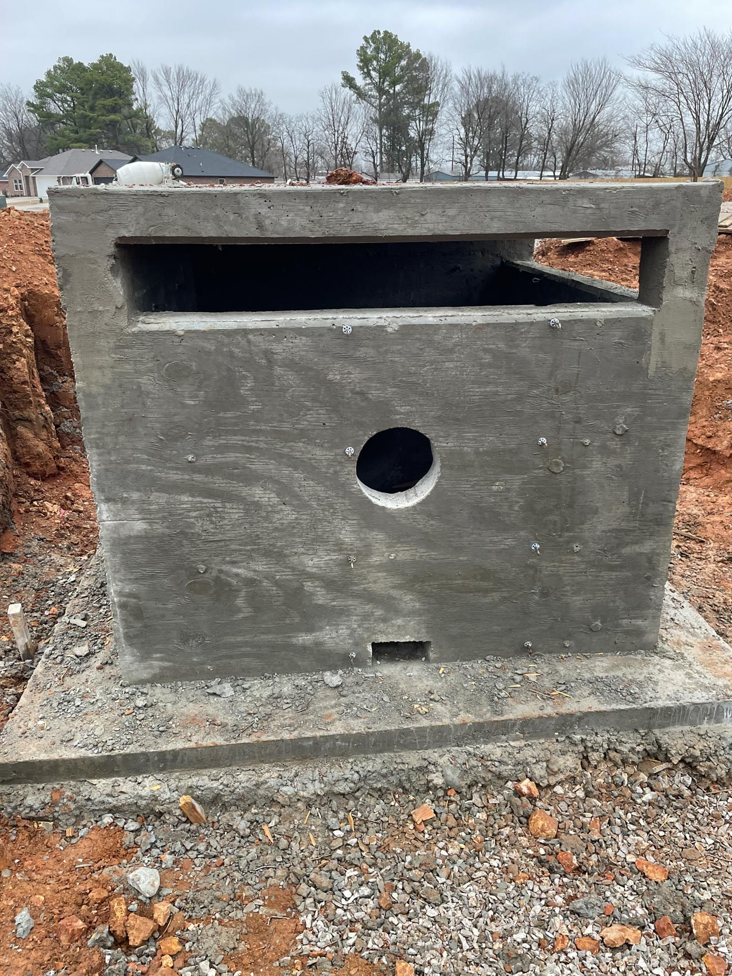 A concrete box with a hole in the middle is sitting on top of a pile of gravel.