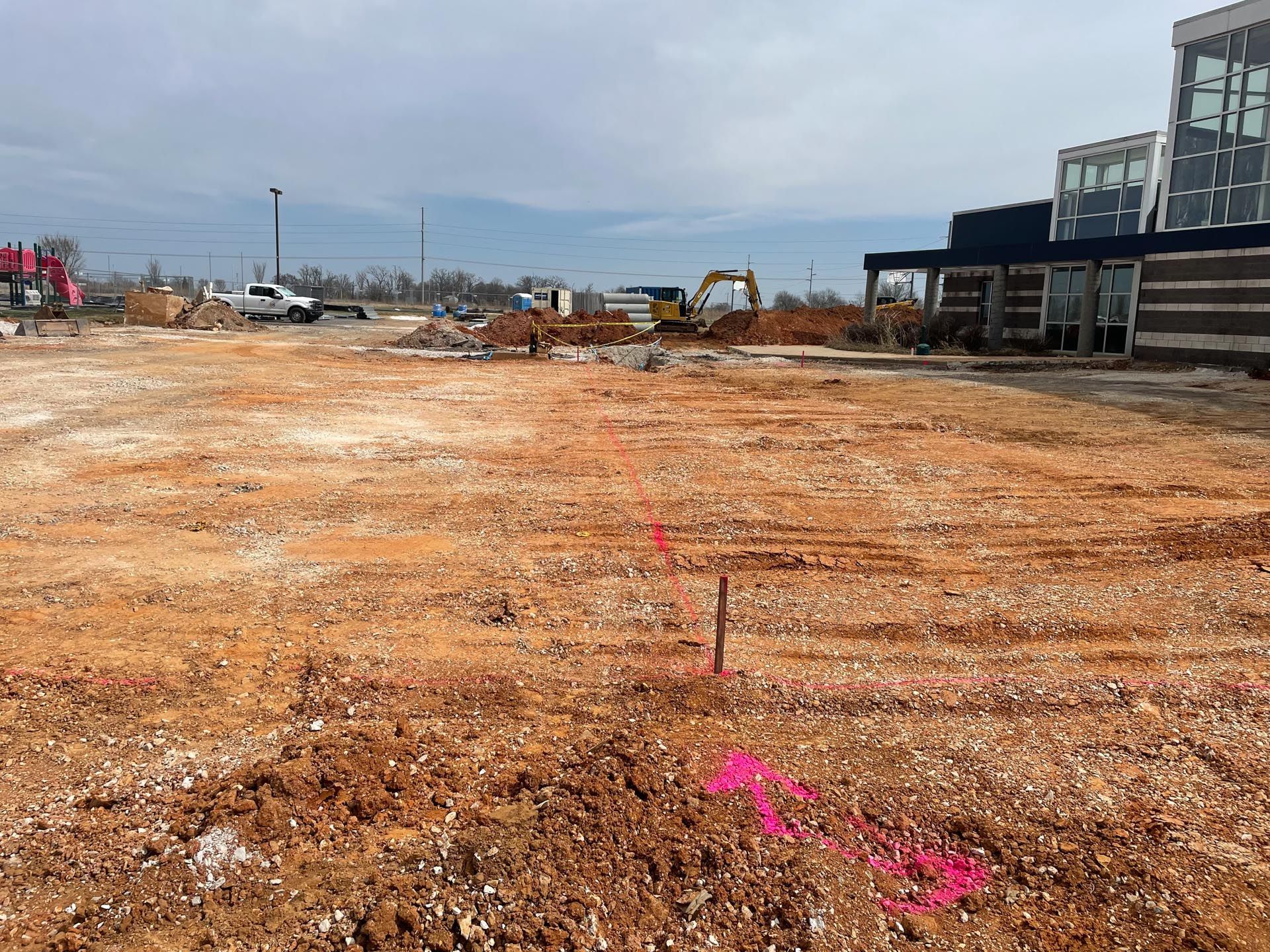 A construction site with a lot of dirt and a building in the background.