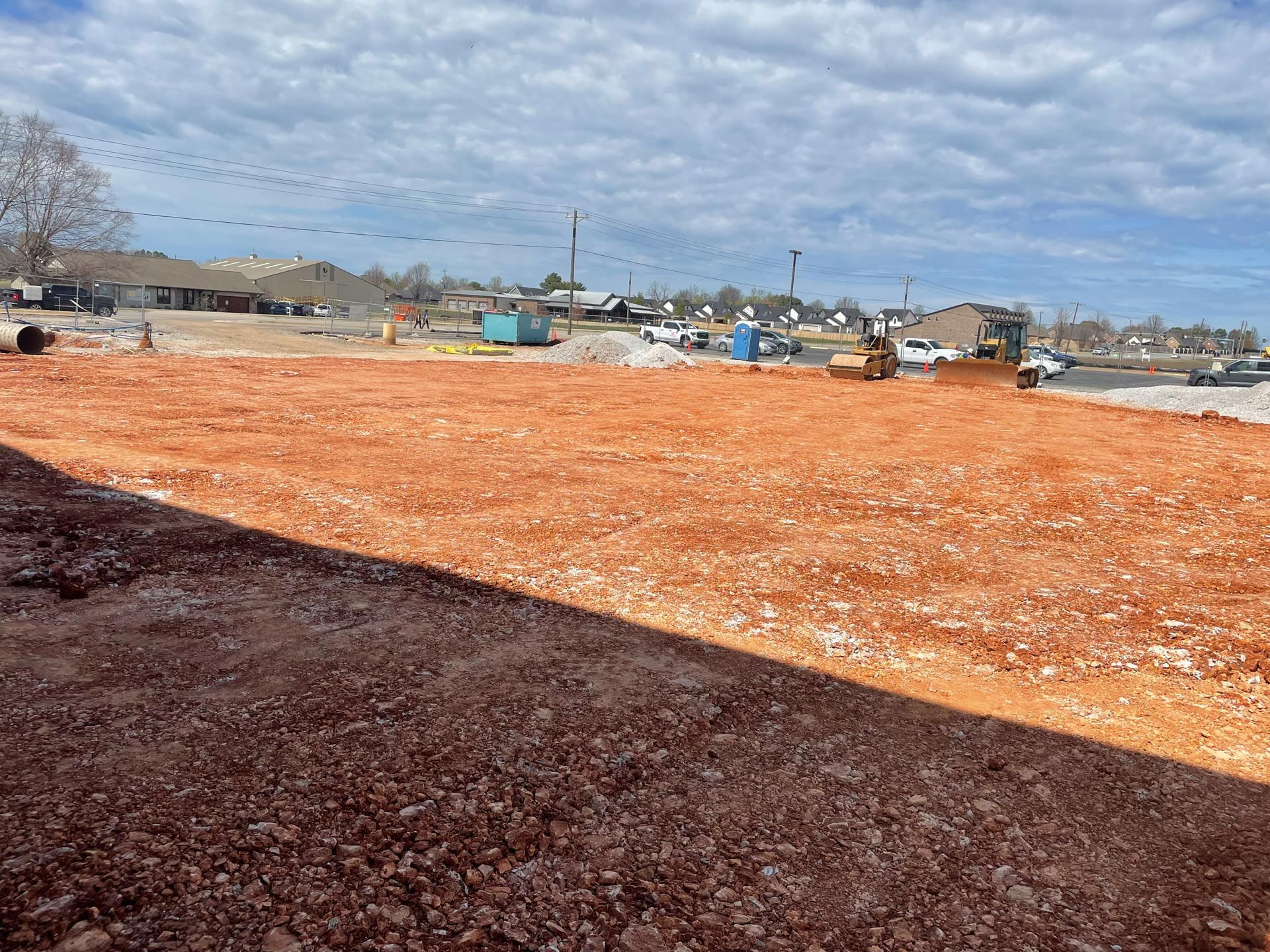 A construction site with a lot of dirt and buildings in the background.