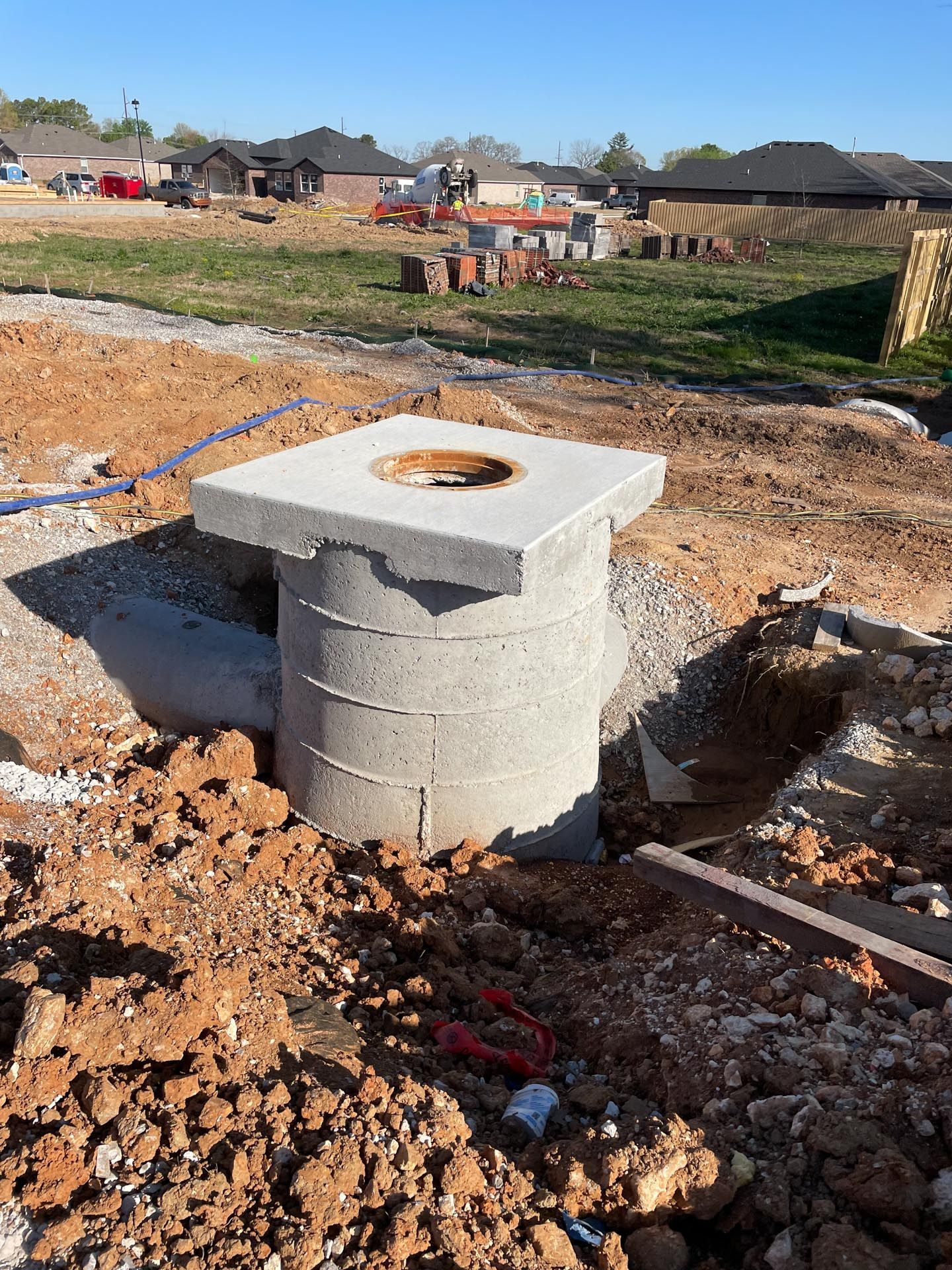 A concrete cylinder is sitting in the middle of a pile of dirt.