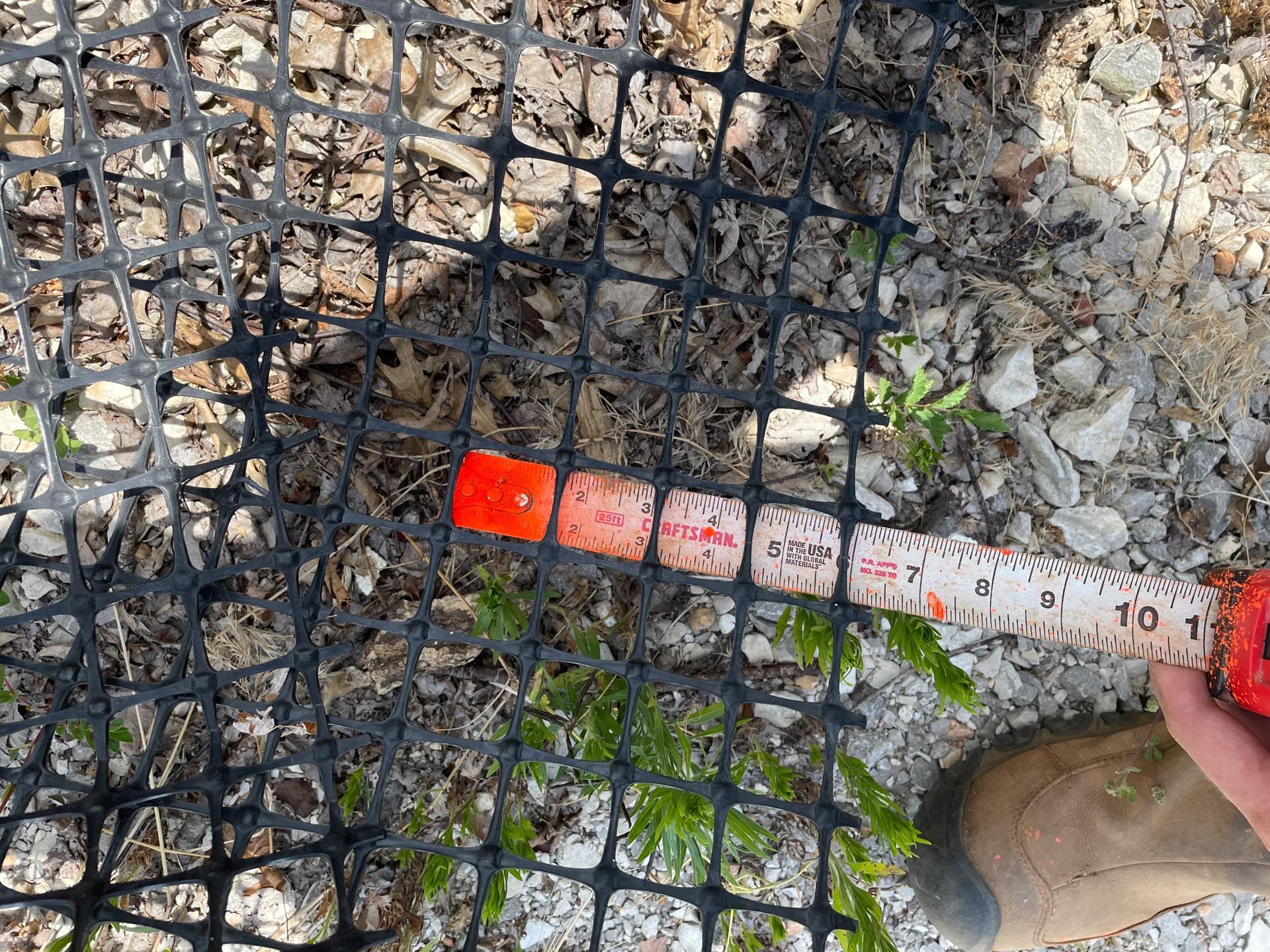 A person is measuring a fence with a tape measure.