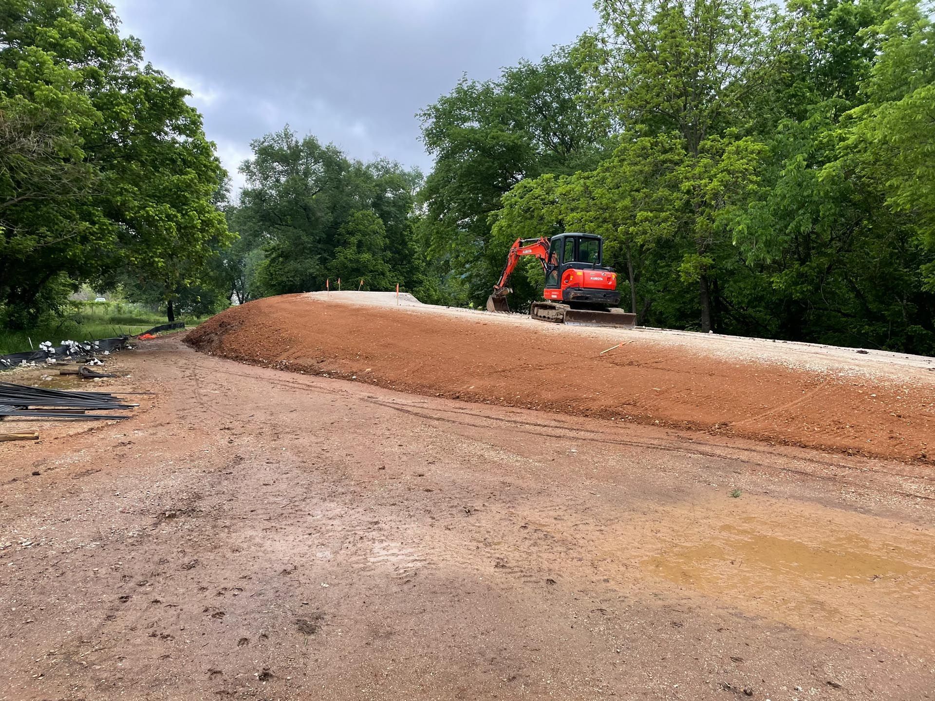 A red excavator is driving down a dirt road.