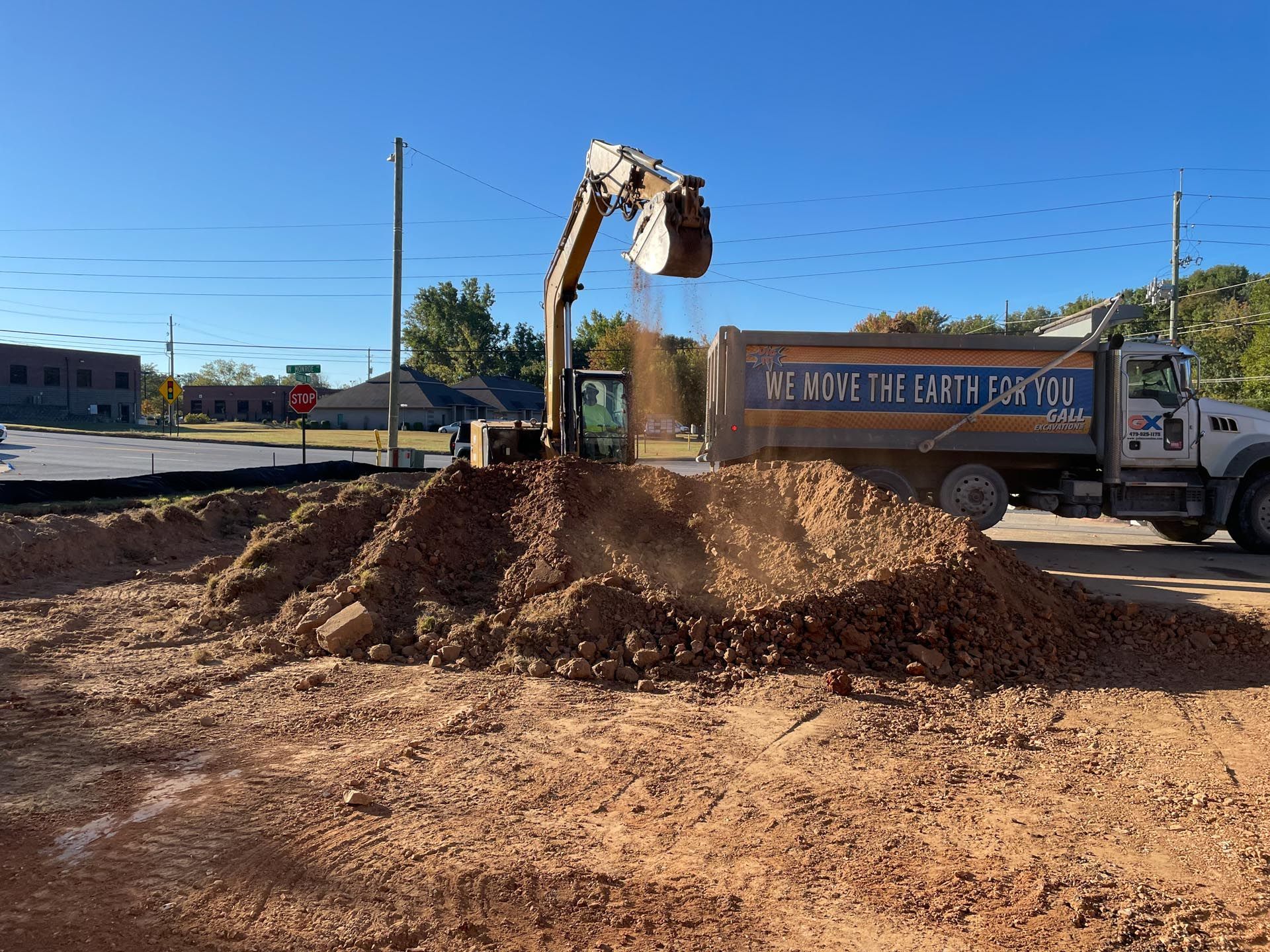 A dump truck is being filled with dirt by a bulldozer.