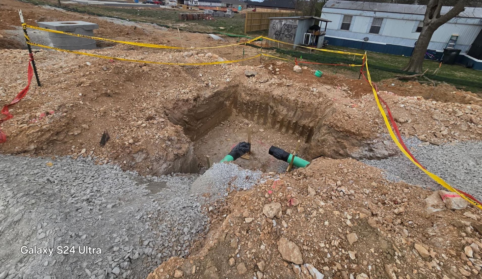 A hole in the ground with a green pipe in it.