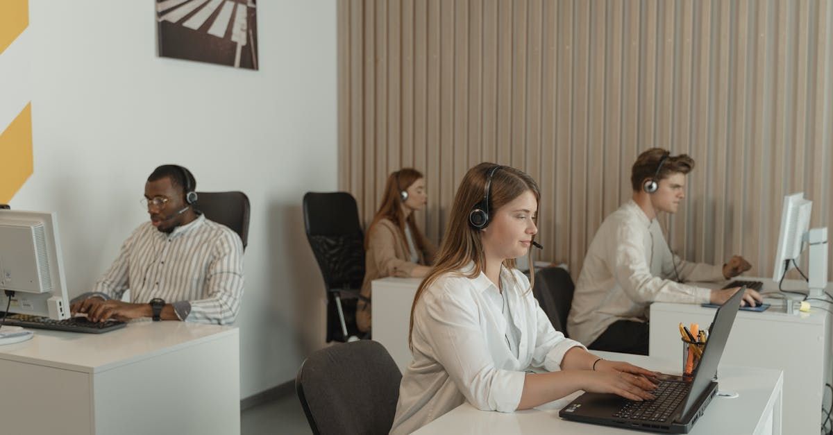 A group of people are sitting at desks in front of computers in a call center.