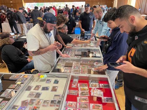 A man wearing a ny hat stands in front of a table full of cards