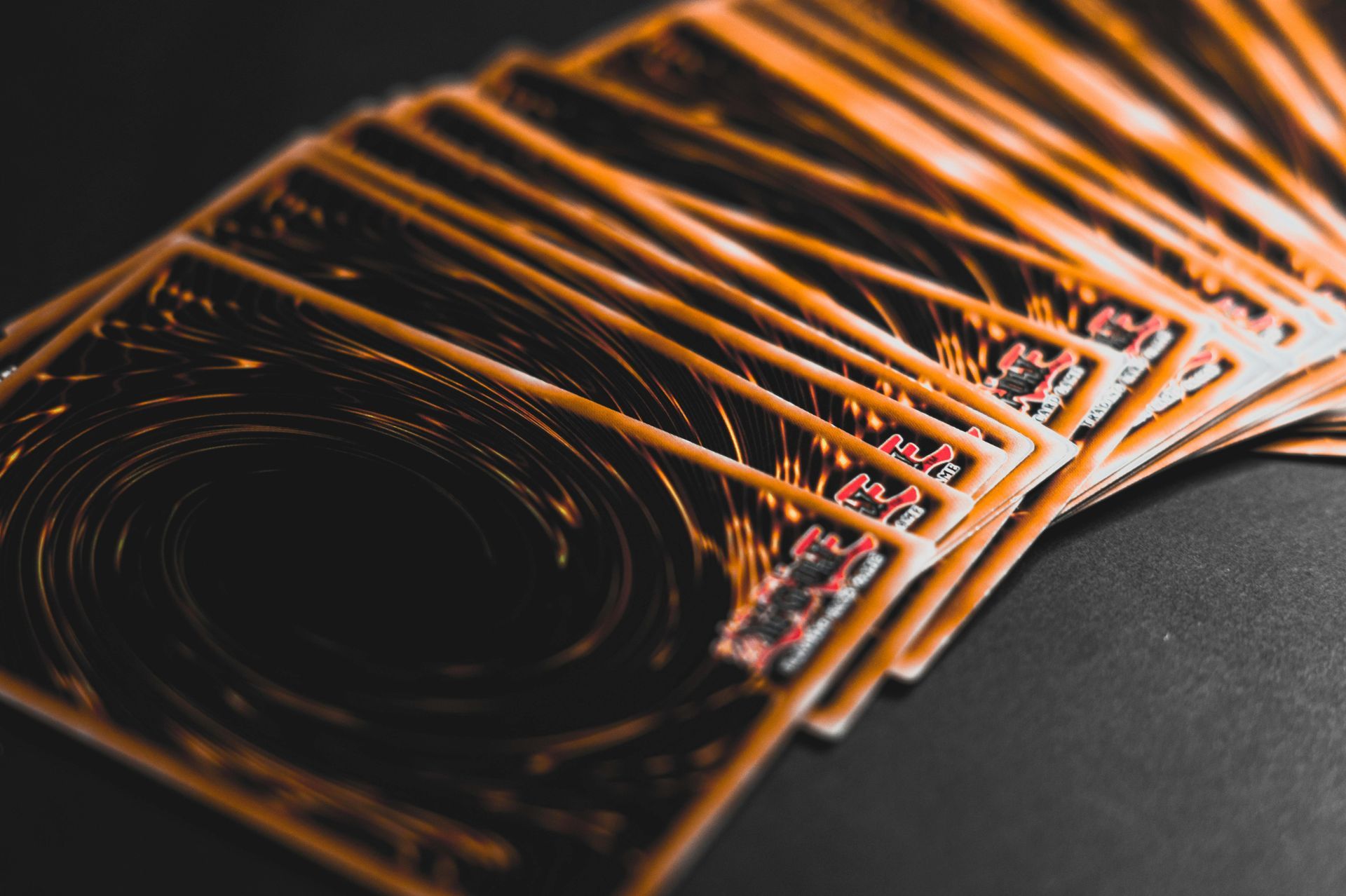 Yu-Gi-Oh! card backs fanned out on a dark surface, showing a swirling design.