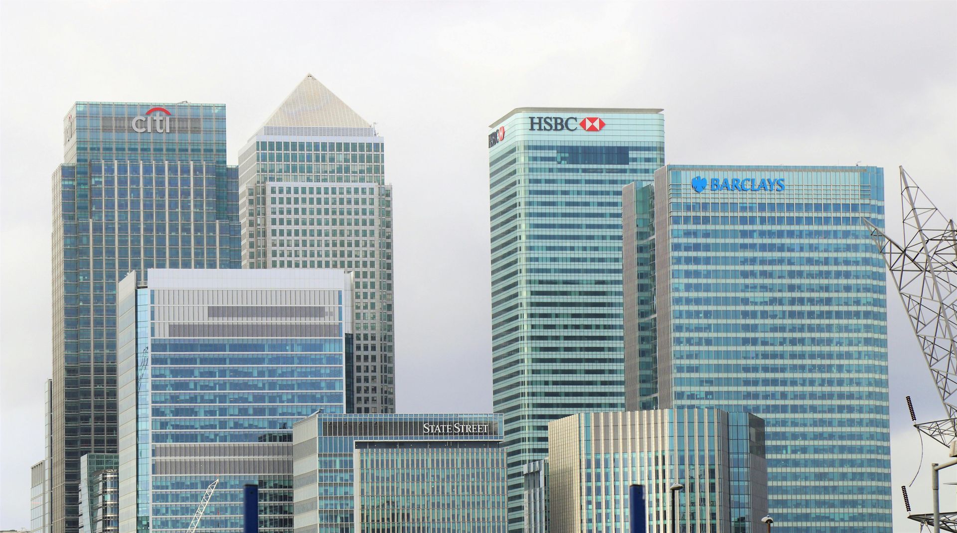 A cluster of modern skyscrapers in Canary Wharf, London, featuring the HSBC, Citi, and Barclays corporate buildings.