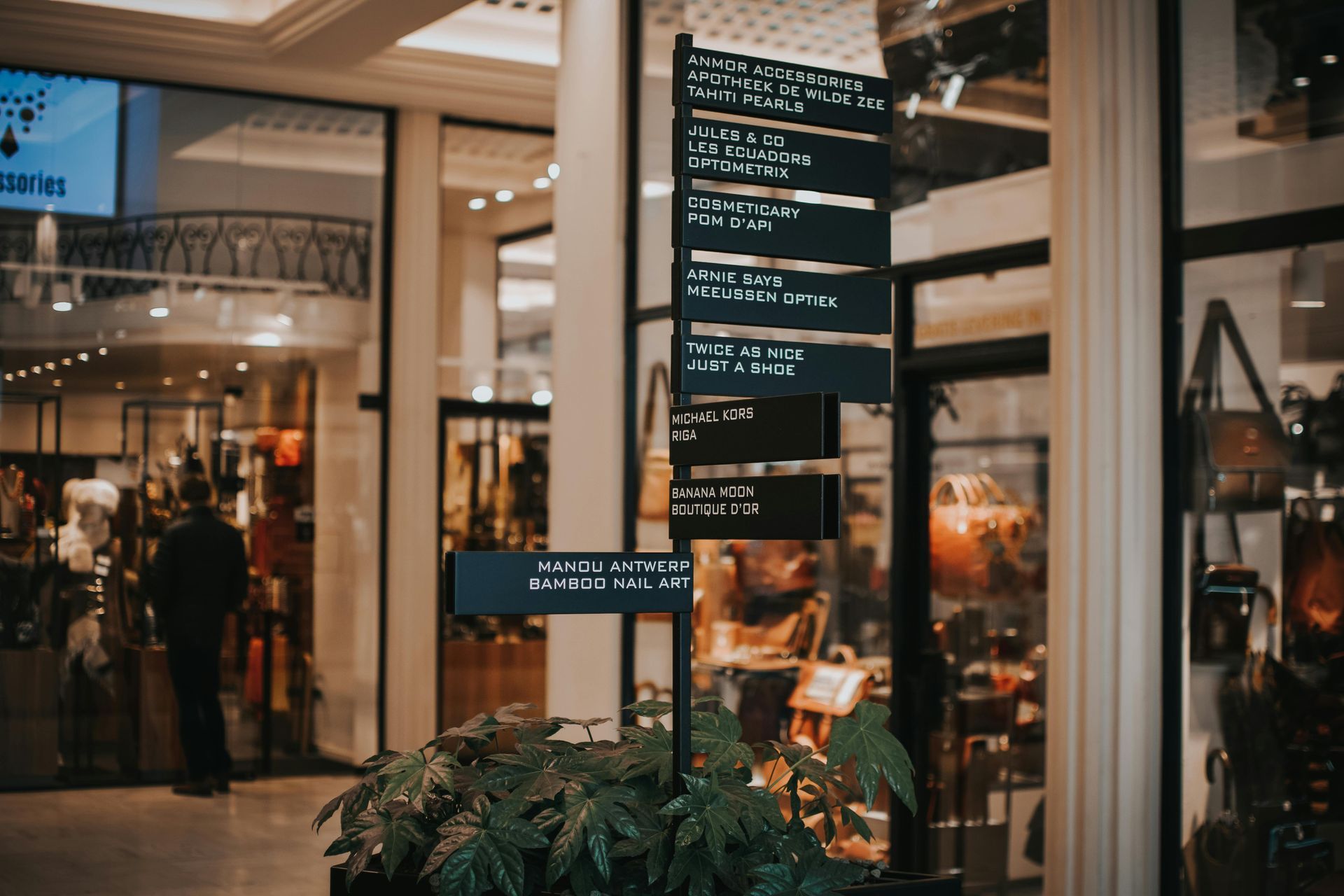Mall directory sign with store listings, in front of shops.