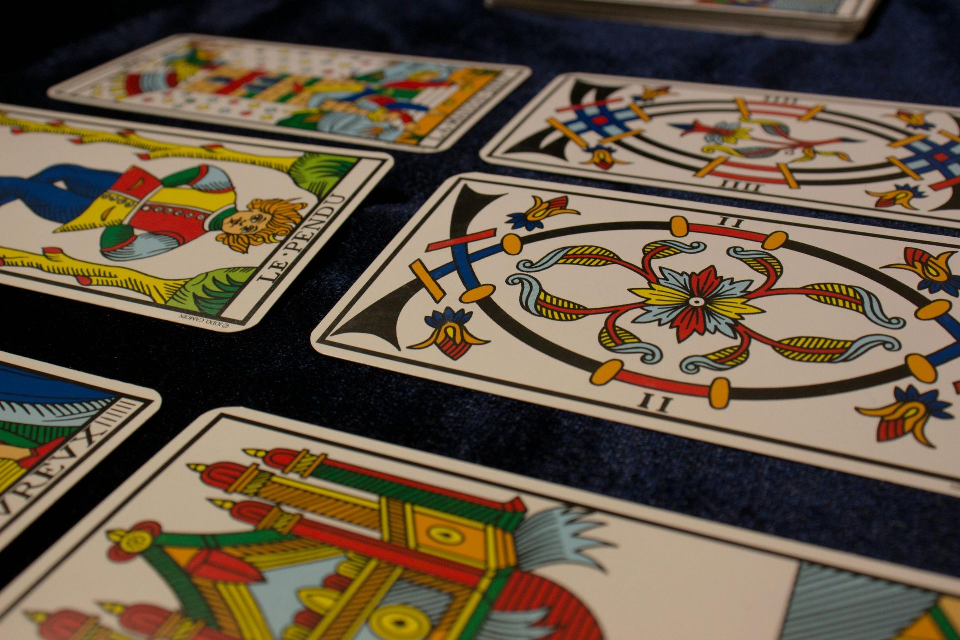 Tarot cards laid out on a dark blue surface, showing colorful illustrations.