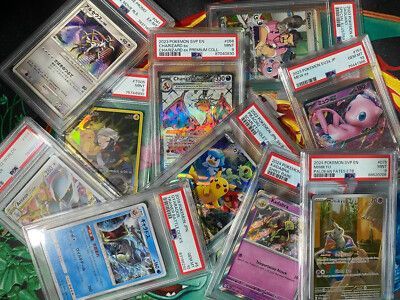 Pile of graded Pokémon cards in protective cases. Featuring Charizard, Pikachu, Mew, and other holographic cards.