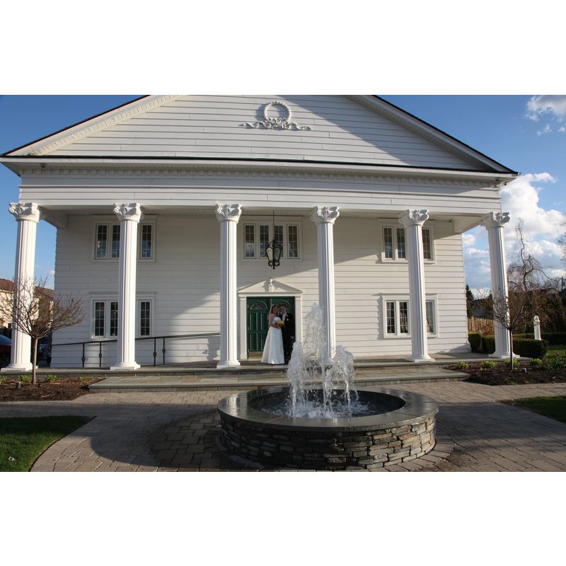 A white building with a fountain in front of it