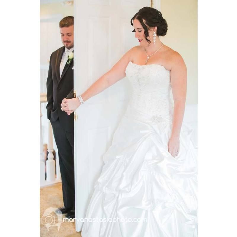A bride and groom are standing in a room holding hands