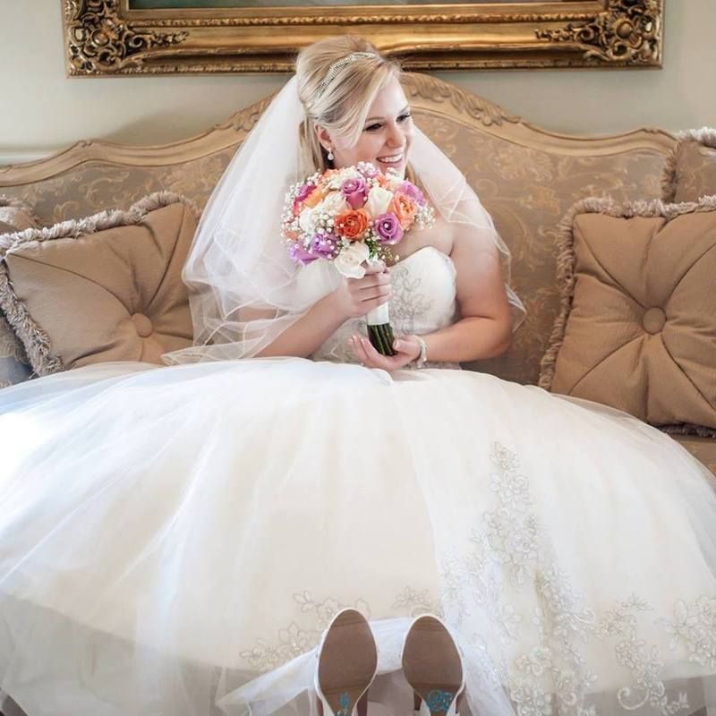 A bride is sitting on a couch holding a bouquet of flowers