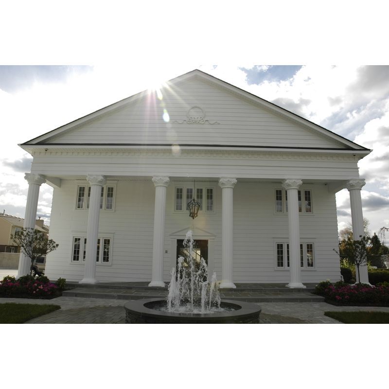 A large white building with columns and a fountain in front of it