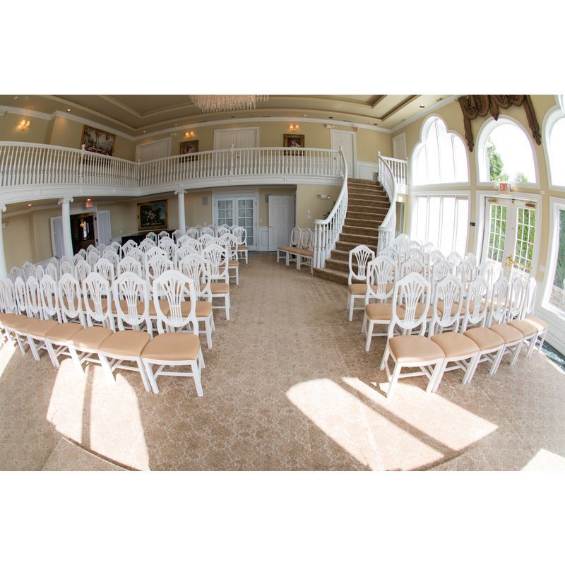 Rows of white chairs in a large room with stairs
