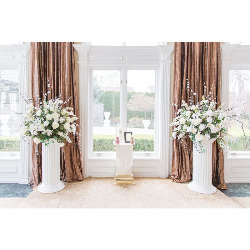 There are two vases with flowers in them in front of a window.