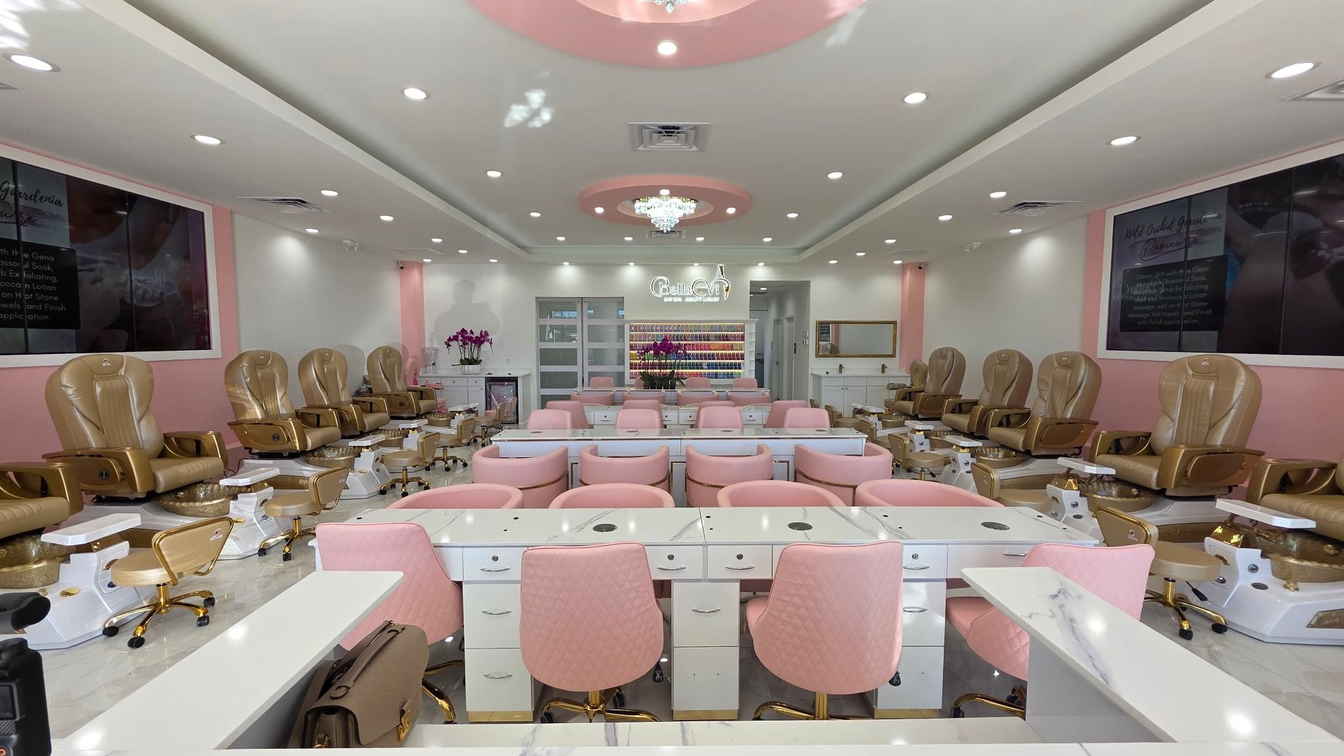 A large nail salon with pink chairs and tables.