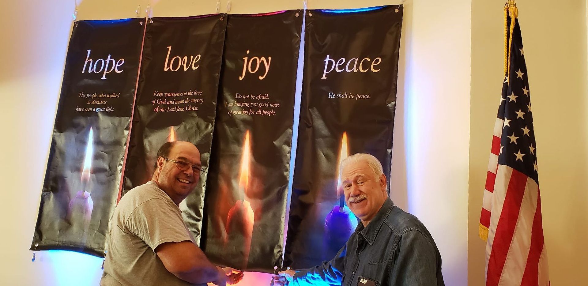 Two men are standing in front of banners that say hope love joy peace