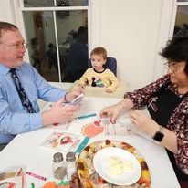 A man and a woman are sitting at a table with a baby in a high chair.