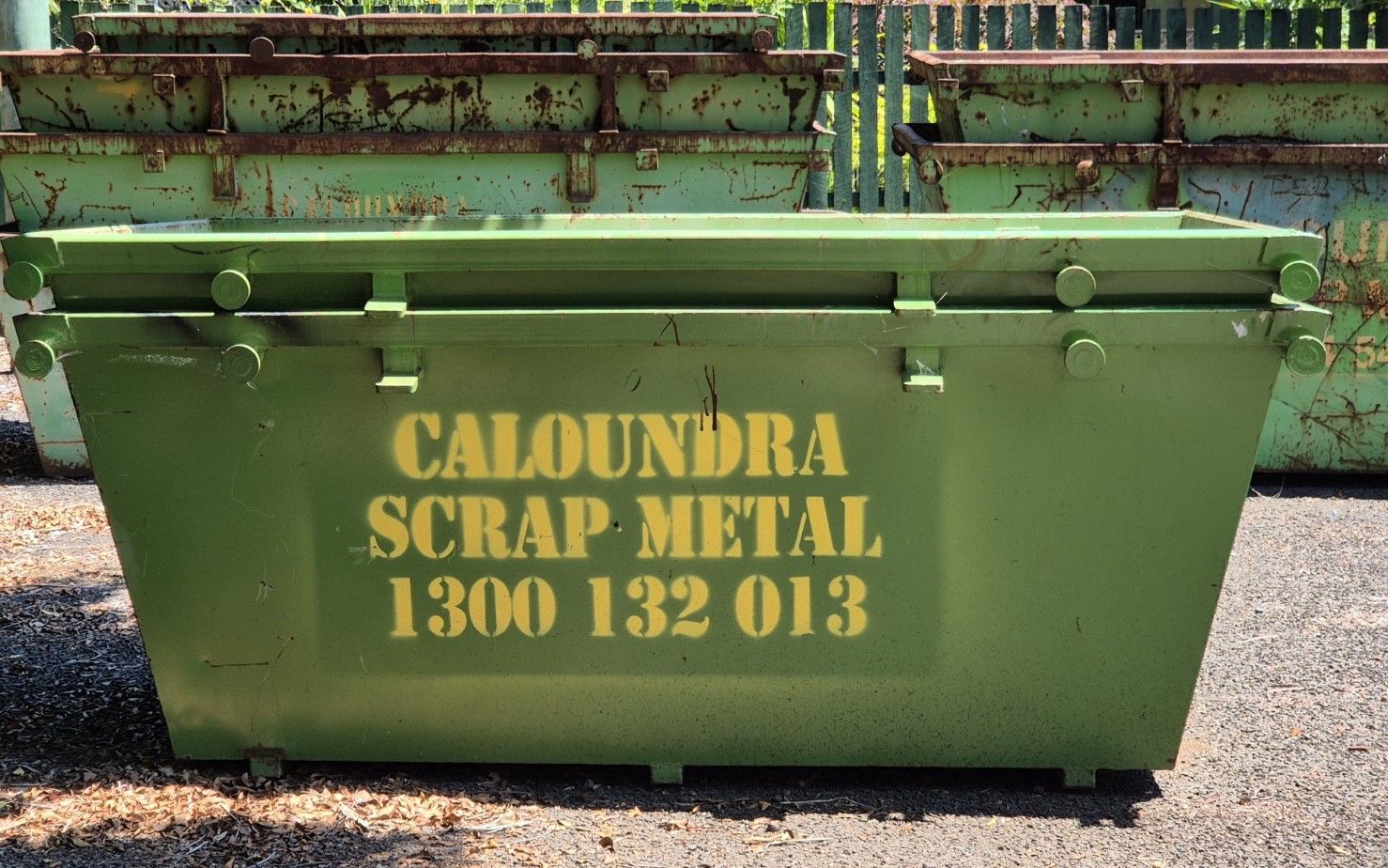 A Green Dumpster Is Sitting On Top Of A Lush Green Field — Caloundra Scrap Metal in Landsborough, QLD