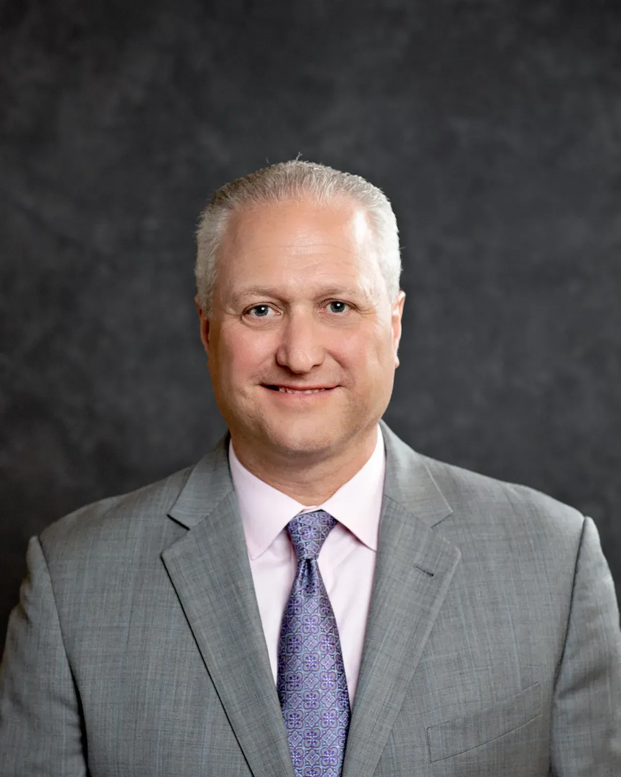 A man in a suit and tie is smiling for the camera.
