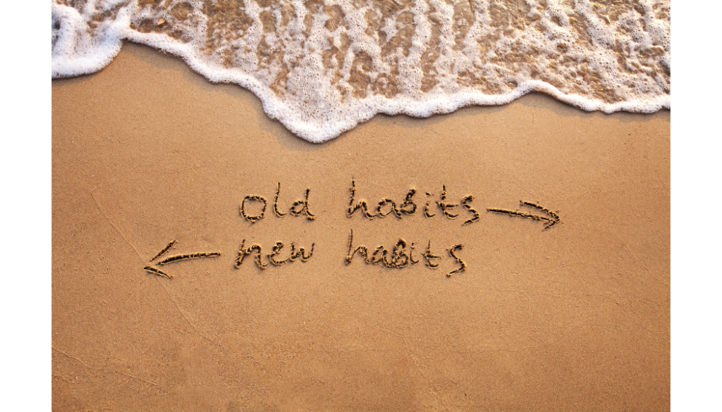 The words old habits and new habits are written in the sand