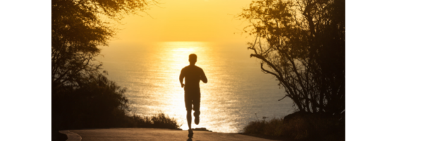 A silhouette of a man running on a road at sunset.