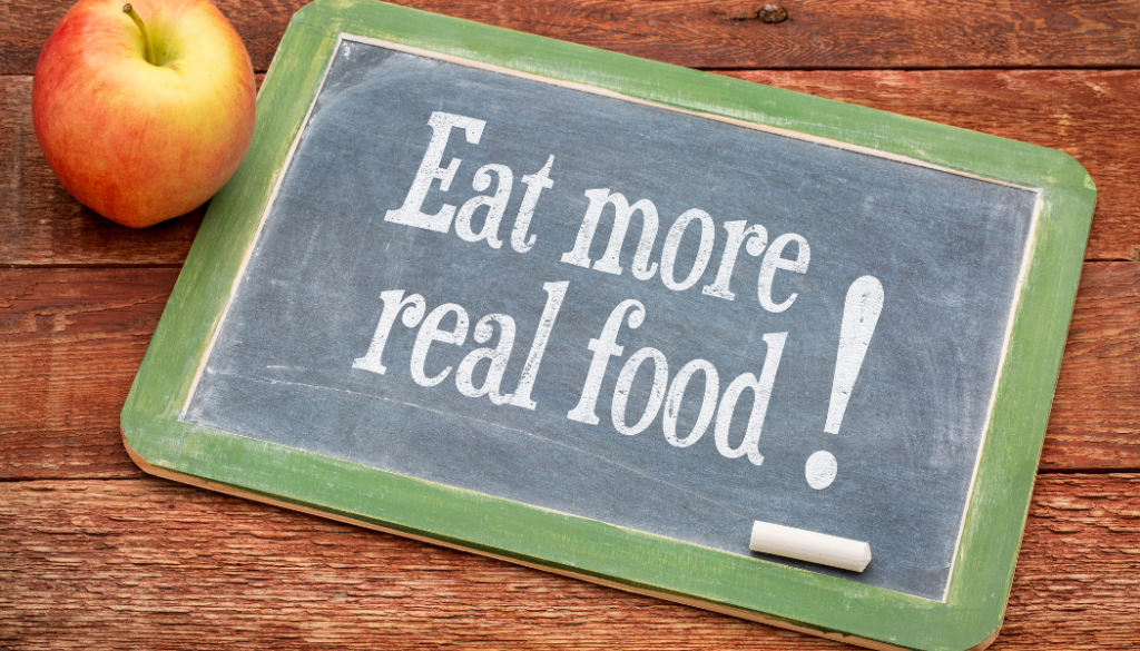 A chalkboard with the words `` eat more real food '' written on it.