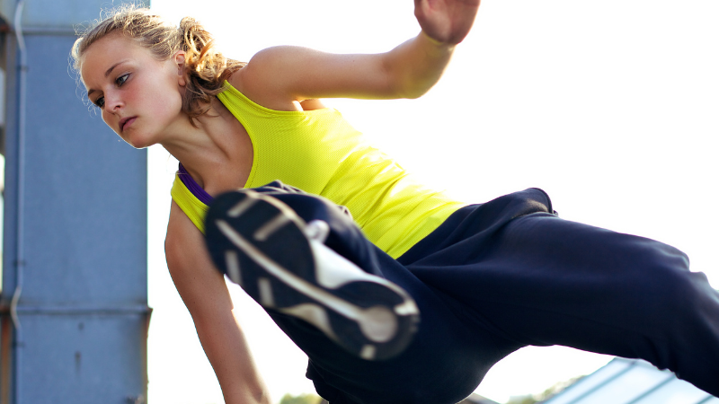 A woman in a yellow tank top is doing a trick